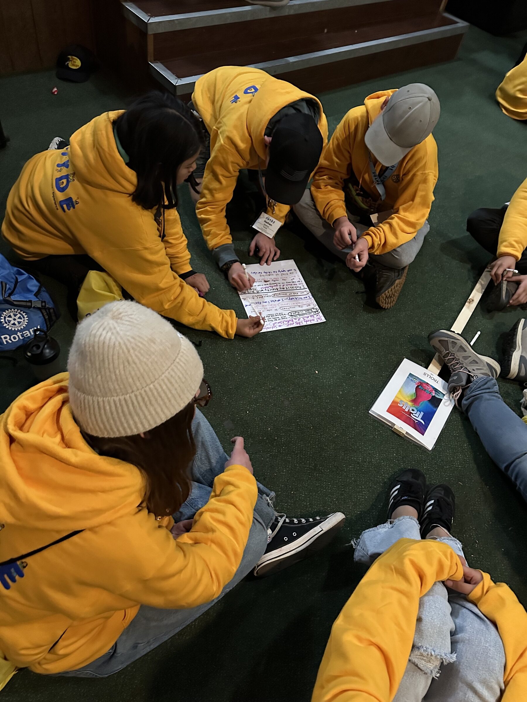 A small group of campers sitting on the floor, writing together on a shared worksheet
