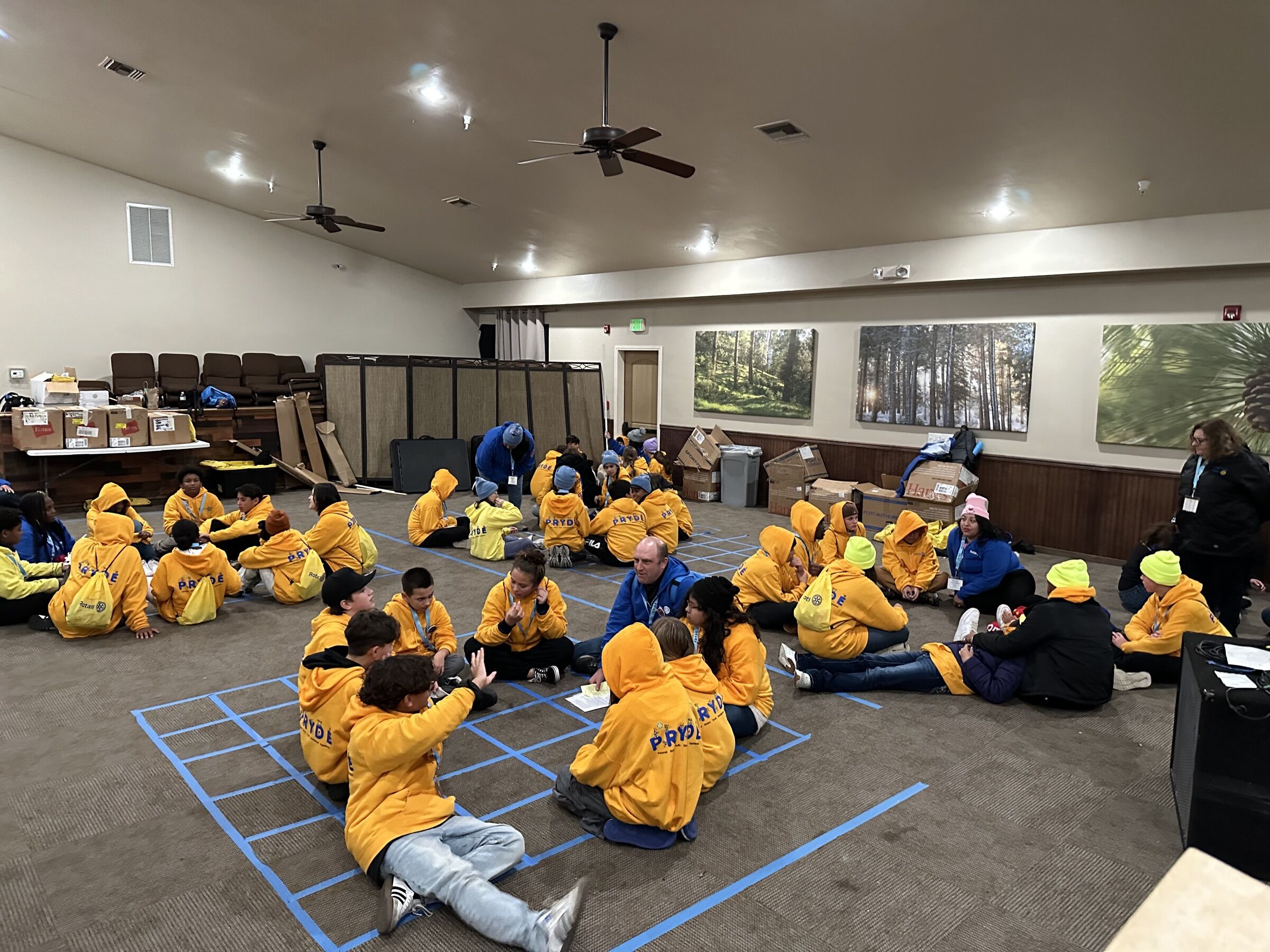 Campers seated in small groups on the floor, with a Rotarian leader joining one of the groups